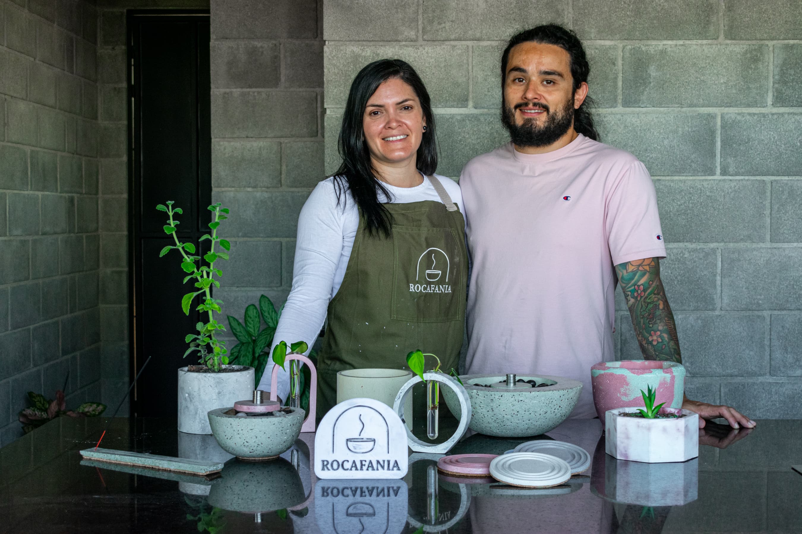 The ROCAFANIA team behind a table with concrete planters, propagation kits, a fire bowl and coasters